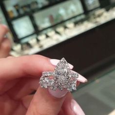 a woman's hand holding an engagement ring in front of a jewelry store display