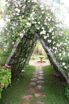 an arch made out of branches with flowers on the side and a fire hydrant in the middle