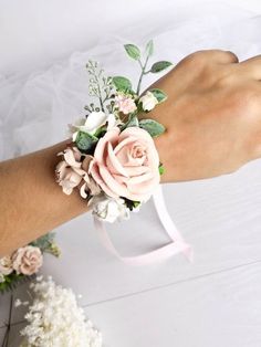 a woman's hand with a pink wrist corsage and flowers on it