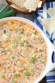 a white casserole dish with tortilla chips and green onions on the side