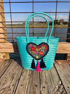 Fall in love with this beautiful tote bag.  Not only is this bag spacious, it is also unique. It features a heart with tassels on the front. The design in the heart is hand embroidered, no 2 designs are exactually alike.   Size is approximately 14 in Length 11 Height (without handles) 6.5 Width Woven Bucket Shoulder Bag As Gift, Woven Shoulder Bucket Bag As Gift, Woven Shoulder Bucket Bag For Gift, Bucket Bag With Braided Handles For Gift, Bucket Shoulder Bag With Braided Handles As Gift, Basket Shaped Shoulder Bag With Braided Handles As Gift, Basket Shoulder Bag With Braided Handles As Gift, Gift Basket Bag With Braided Handles, Handmade Turquoise Bags For Summer