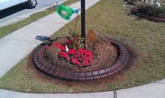 a street sign on the side of a road next to flowers and a potted plant