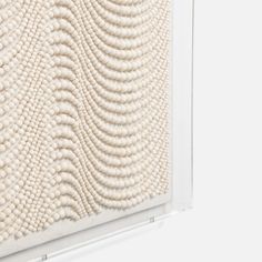 a white wall hanging on the side of a building next to a window covered in beads