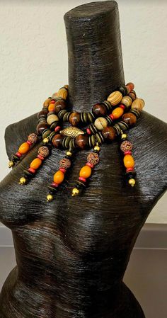 This piece is showy and dramatic, yet very lightweight and comfortable to wear. A triple strand statement necklace supports five beaded wire dangles, which can simply be straighted should they ever get bent. The statement necklace features a golden repousse bicone bead, wood rondelles, oversized big round chocolate beads, blonde wood barrels, conch shell, coral rondelles, vintage Chinese brass coins, Moroccan resin, picture jasper, etched brown resin with a dragon motif, black plastic spacers an Luxury Statement Beads, Gems, And Cabochons, Dragon Motif, Get Bent, Blonde Wood, Statement Bib Necklace, Chest Piece, Autumn Wardrobe, Metal Ball, Conch Shell