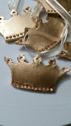 three pieces of gold metal sitting on top of a white table next to a ribbon