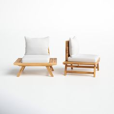 two wooden chairs with white pillows on them