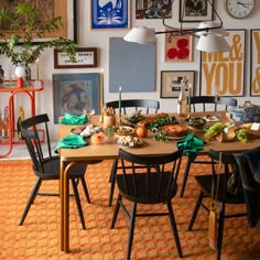 a dining room table is set with food and decorations on the wall, along with several framed pictures