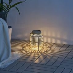 a light shines on the floor next to a potted plant and a white blanket