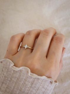 a woman's hand wearing a gold ring with two small white diamonds on it