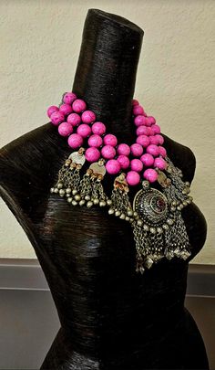 This stunning and very feminine tribal - ethnic creation consists of 20 mm hot pink magnesite round beads, hematite spacers and very ornate silver tone beads in the back. A vintage Waziri dome with chain dangles is the focal pendant (some of the inlaid glass is missing but this is fairly commonplace for older Middle Eastern pendants such as this). Additionally, six vintage Kuchi chain dangles are suspended from the outermost strand. If you look closely at the Kuchi dangles, you will notice something that looks like rust, which it is not. This is the type of solder that was used, and you could almost liken it to a patina. You can compare the current photo's with the last four which were taken in May of 2023 to see that there is no change. Personally, I like this since it adds to the age and Traditional Handmade Pink Beads, Bohemian Pink Necklace With Polished Beads, Pink Bohemian Jewelry For Festivals, Traditional Pink Necklaces With Dangling Beads, Pink Festival Jewelry With Latkans, Pink Latkan Festival Jewelry, Pink Bohemian Beads With Dangling Details, Bohemian Pink Jewelry With Large Beads, Pink Bohemian Jewelry With Large Beads