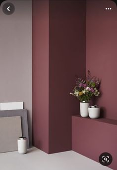 two vases with flowers are sitting on the ledge in front of a purple wall