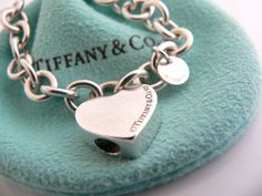 Offered for sale is a wonderful and rare Tiffany and Co. Sterling Silver "Mom" Heart Padlock bracelet. The piece is made from substantial and bright Tiffany silver, and yet retains a very feminine feel to it. Attached to its very substantial Tiffany Silver charm bracelet is a Heart padlock charm with the word "Mom" engraved in beautiful script. The"Mom" padlock charm opens and closes and thus can be used as a charm on a necklace or as part of another charm bracelet! Super versatile piece! It is Luxury Heart Charm Bracelet For Anniversary, Luxury Heart Cut Bracelet As Gift, Luxury Heart-cut Bracelet For Gift, Luxury Heart Cut Bracelet For Gift, Luxury Heart Bracelet For Wedding, Luxury Heart-shaped Bracelet For Wedding, Luxury Sterling Silver Heart Bracelet For Gift, Luxury Sterling Silver Heart Bracelet For Valentine's Day, Heart-shaped Hallmarked Bracelets As A Gift