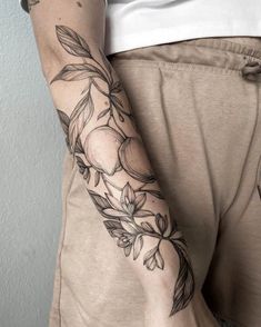 a woman's arm with tattoos on it and flowers in the middle of her arm