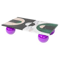 a marble table with purple and green balls on the top, in front of a white background