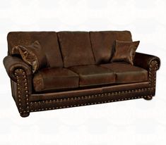 a brown leather couch with lots of pillows on it's back and armrests