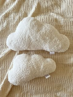 two pillows that are on top of a bed covered in white linens and one is shaped like a cloud