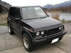 a black suv parked in front of a body of water