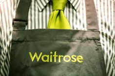 a man wearing a green tie holding a black bag with the word waitrose on it