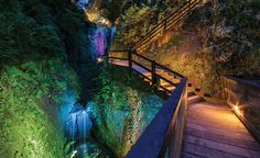 a wooden walkway leading to a waterfall at night