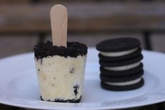 an ice cream sundae with oreo cookies on the side and a wooden stick sticking out of it