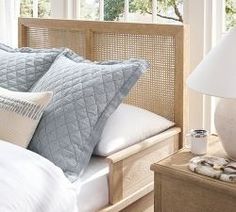 a bed with white pillows and blue quilts on top of it next to a night stand