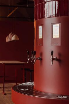 a large red water heater sitting on top of a wooden floor next to a table