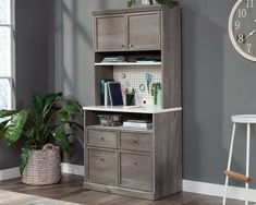 a grey bookcase with drawers and a clock on the wall