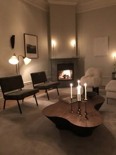 a living room filled with furniture and a fire place next to a table covered in candles