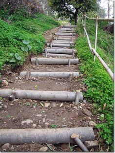 a set of stairs made out of pipes on the side of a hill with grass and trees in the background