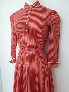 Amazing vintage 70's shirt dress by Adele Simpson!!Features include:Red and white stripe dress with nipped waistlineWhite eyelet trim at cuffs and collarButtons up front from neckline to mid hip lengthCute folded cuffsAdele Simpson label insideEra:1970'sMeasurements:Shoulder to shoulder - 14"Around chest, underneath armpits - 35"Across waist - 24""Across hips - 42"Top of shoulder to bottom hem - 45"I'd say this would best fit a size S or XS, but please consult measurements for an accurate fit!Al Classic Striped Button-up Shirt Dress, Striped Fitted Cotton Shirt Dress, Fitted Striped Cotton Shirt Dress, Striped Cotton Shirt Dress With Buttons, Fitted Striped Shirt Dress With Buttons, Classic Striped Cotton Dress, Classic Summer Dress With Striped Collar, Fitted Striped Shirt Dress For Daywear, Classic Striped Dresses For Daywear