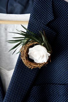 a close up of a suit with a flower in the center and a twig sticking out of it