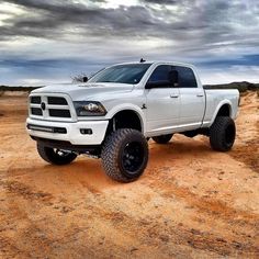 a white ram truck parked on top of a dirt covered field in the middle of nowhere