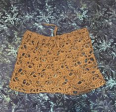 an orange crocheted skirt sitting on top of a blue and white table cloth