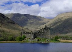 a castle sitting on top of a lake surrounded by mountains