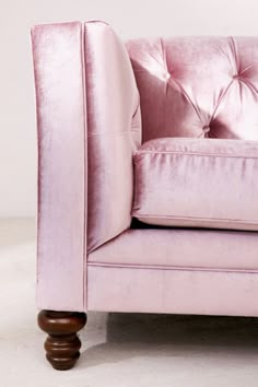 a pink velvet chair sitting on top of a white floor