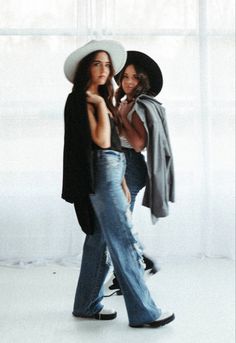 two women in jeans and hats are posing for the camera