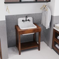 a white sink sitting under a bathroom mirror next to a wooden stand with clothes hanging on it