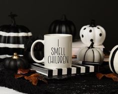 black and white pumpkins are sitting on a table with two coffee mugs in front of them