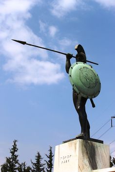 a statue of a man with a spear and shield on his back holding a ball