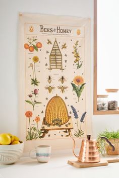 a kitchen counter with a tea pot, plate and mug on it next to a beehive poster