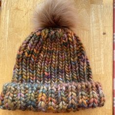 a multicolored knitted hat with a pom - pom on top