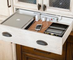 an open drawer in the middle of a kitchen counter with electronics and cords attached to it