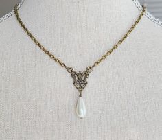 "This beautiful necklace features a beautiful brass filigree pendant with glass pearl teardrop. The necklace is reminiscent of pieces seen in classic portraits of the past. It hangs 16 1/2 \" long from a nickel free brass chain with lobster clasp and has a 2\" long extender chain with glass pearl detailing. Comes in a lovely gift box with ribbon. In the Eighteenth and Nineteenth centuries necklaces were very fashionable. Some were made of pearls, glass or gemstones and can be seen in many classic portraits. I think they're a very elegant accessory." Elegant Antique Gold Pendant Necklace, Elegant Brass Necklace With Intricate Design, Elegant Pendant Necklaces With Historical Design, Elegant Historical Pendant Necklaces, Victorian Pearl Drop Necklace, Victorian Pearl Necklace For Formal Occasions, Elegant Brass Jewelry For Vintage Events, Elegant Antique Gold Necklaces For Gift, Elegant Antique Gold Necklace For Gift