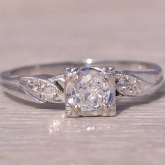 a white gold ring with an old - cut diamond and two smaller diamonds on the band