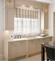 a large kitchen with white cabinets and marble counter tops