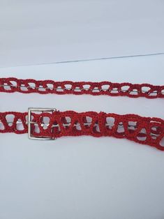 two red crocheted belts with metal buckles