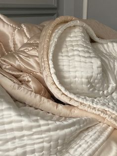 an unmade bed with a white comforter on top of it and a pillow under the covers