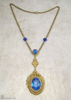 "(Description is below) ALL DELIVERY DATES mentioned by Etsy are ESTIMATES, no delivery date or range is guaranteed, though most of our orders arrive ahead of estimate.  LAYAWAY IS AVAILABLE, typically with a 20% deposit. Please contact us to arrange.  Old, probably late 19th or early 20th century, brass filigree and faceted blue glass pendant necklace in a transitional Victorian / Edwardian style. The largest portion of pendant measures about 2.25\", with a total center drop of just over 4\", t Blue Brass Jewelry For Wedding, Antique Sapphire Filigree Jewelry, Antique Sapphire Jewelry With Filigree, Antique Blue Metal Jewelry, Antique Blue Brass Jewelry, Vintage Blue Jeweled Necklaces, Antique Blue Oval Pendant Jewelry, Blue Antique Jewelry With Antique Finish, Vintage Sapphire Pendant Necklaces