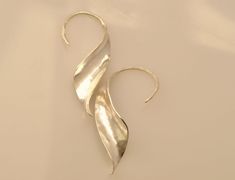 "I make these earrings from a sheet of sterling silver, using the hammering technique called anticlastic raising. This technique allows the earrings to be strong and light at the same time. These earrings are beautiful from any angle, and so can be worn in three different ways, equally striking: switching the one on the left ear with the one on the right gives you a different look, as does reversing the placement of the \"ear wire\" and earring body, so that the ear wire sits on the outside of t Luxury Metal Earrings With Ear Wire, Luxury Sterling Silver Ear Wire Jewelry, Luxury Hand Forged Earrings For Women, Unique Hammered Sterling Silver Earrings, Artistic Sterling Silver Teardrop Earrings, Artisan Silver Long Drop Earrings, Artisan Long Drop Silver Earrings, Elegant Hand Forged Silver Earrings, Elegant Hand-forged Silver Earrings