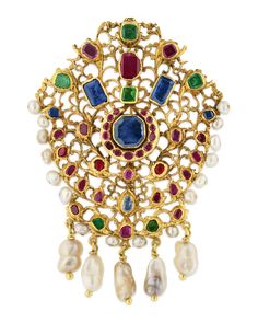 This historic gold brooch hails from the illustrious Mughal Empire and showcases the beauty of traditional jadau jewelry. Using the jadau technique, artisans create a gold frame into which precious stones and other treasures can be imbedded. Almost certainly once worn as adornment for a turban or other head covering, the creation has been modified to be wearable as both a pendant and brooch. The 14K yellow gold brooch showcases colored gemstones with vibrant red, green and blue hues, as well as Mughal Empire Jewelry, Mughal Jewelry Royals, Mughal Jewellery, Mughal Jewelry, Bijoux Art Nouveau, Choker Necklace Designs, Mughal Empire, Colored Gemstones, Historical Jewellery